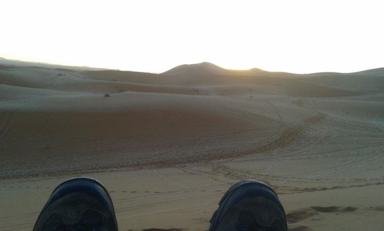 los pies de VHS y el sol al amanecer en el desierto de Sahara